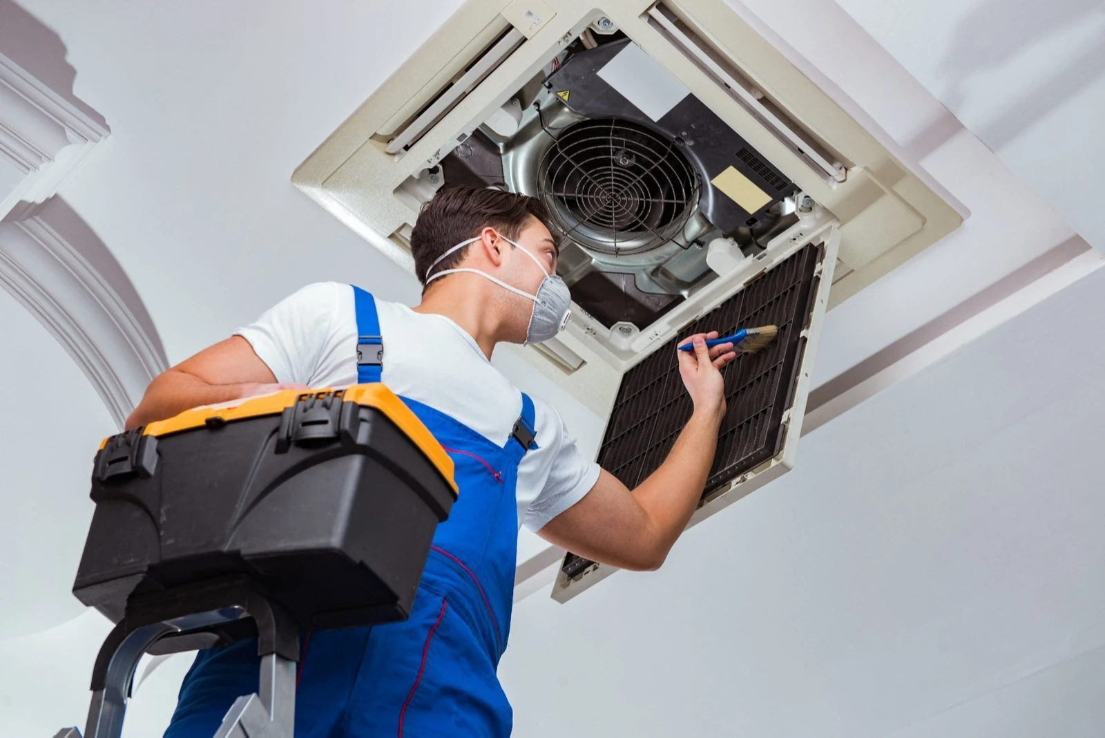 Technician inspecting a ceiling-mounted air conditioning unit