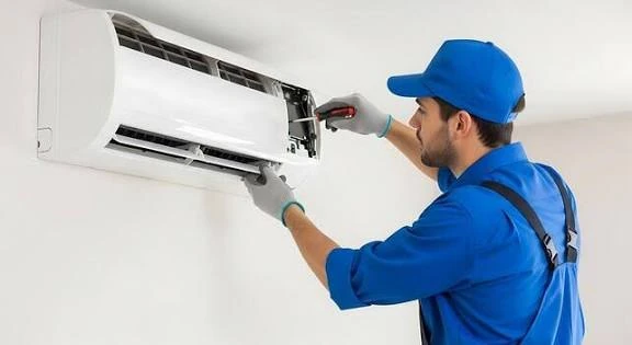 Technician using a screwdriver to service a wall-mounted air conditioner