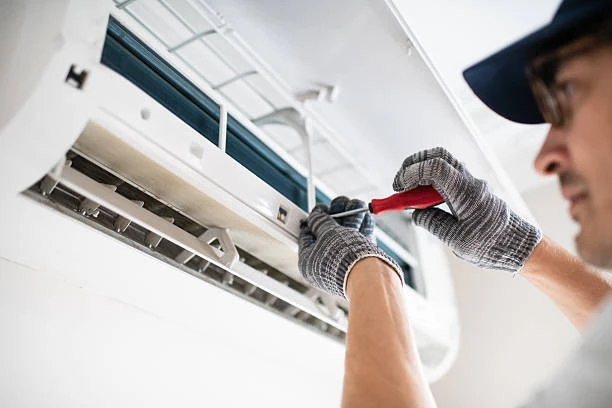 Close-up of a technician adjusting the components of a wall-mounted air conditioner