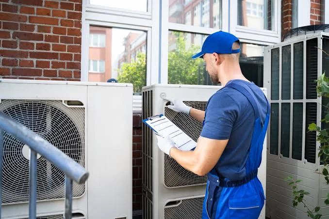 Technician reviewing a clipboard beside outdoor air conditioning equipment